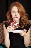 Redhead girl secretly eating cake.